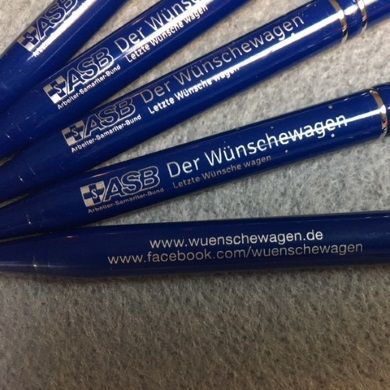 Nahaufnahme von fünf blauen ASB-Kugelschreibern mit Aufdruck „Der Wünschewagen“ sowie Web- und Facebook-Adresse in Silber.