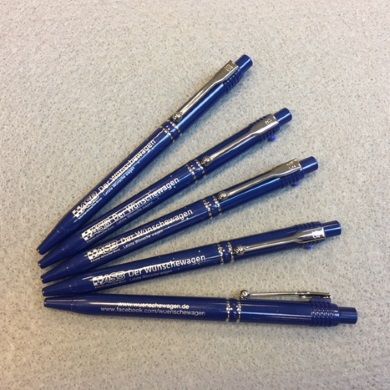 Fünf dunkelblaue Kugelschreiber mit silberner Aufschrift „Der Wünschewagen“ und Website, fächerförmig…